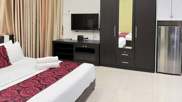 Habitación de hotel con cama, televisor, minibar y refrigerador.