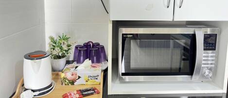 A kitchen with a microwave, a toaster, a box of Unisoff tea bags, and a potted plant.