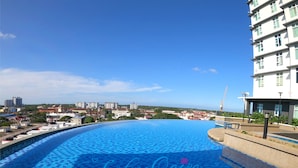 Una amplia piscina infinita de color azul intenso, con vistas a un horizonte urbano.
