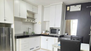 Una cocina moderna con armarios blancos, un refrigerador de acero inoxidable, un microondas y un comedor con mesa y sillas.