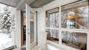 Um quarto com janelas amplas, uma porta e uma cadeira.
