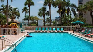 A swimming pool with lounge chairs and palm trees. - Lovely condo on the Bay with inland view! (Marco Island)