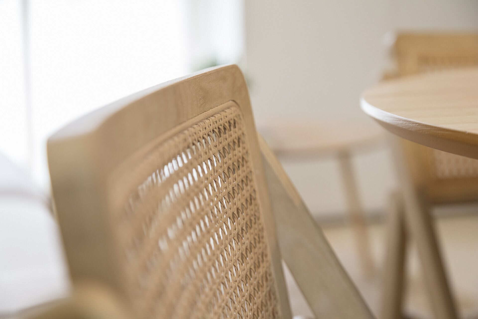 A close-up of a woven chair with a round table in the background.