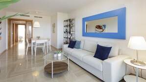 Un salon moderne comprenant un canapé, une table basse et un coin repas avec des chaises.