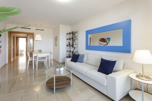 Uma sala de estar moderna com sofá, mesa de centro e um espaço de jantar com cadeiras.