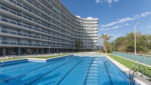 Un hôtel moderne doté d’un bâtiment aux lignes courbes, d’une piscine avec plusieurs couloirs de nage et d’une vue sur les palmiers.