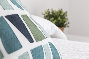 A close-up of a bed with a white quilt and a pillow with a geometric pattern. - Amazing modern style condo, wifi free, interantional channels, heating swimming pool, children's area, BBQ - only families (Playa de Gandía)