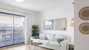 Uma sala de estar moderna com um sofá branco, uma janela grande e uma varanda.