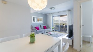 Een moderne woonkamer met een bank, een eettafel en een televisie.