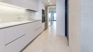 Een moderne keuken met witte kasten, een roestvrijstalen afzuigkap en een ingebouwde oven.