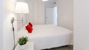 A bedroom with a bed, a bedside lamp, a potted plant, and a wardrobe. - Beautiful condo family near to the beach. Pool / Wifi  - only families (Playa de Gandía)