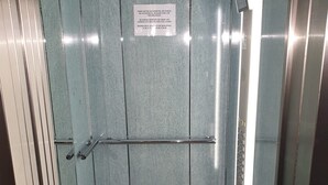 An elevator interior with a metal door, a handrail, and a sign with safety instructions. - Beautiful condo family near to the beach. Pool / Wifi  - only families (Playa de Gandía)
