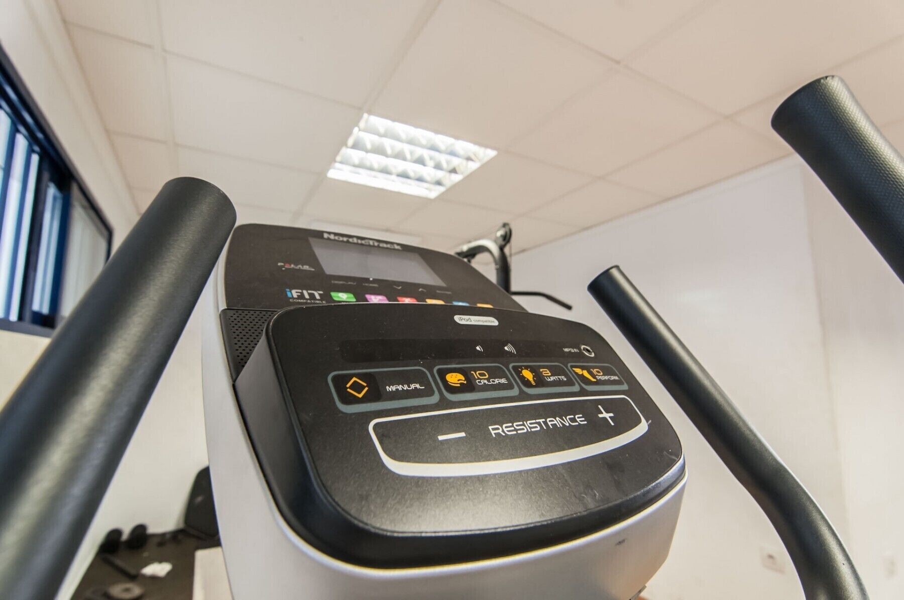 A treadmill with a digital display, control buttons, and a resistance setting.