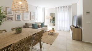 Ein modernes Wohnzimmer mit einem Holzespeisetisch, einem beigen Sofa und einem Fernseher auf einem hölzernen Standfuß.