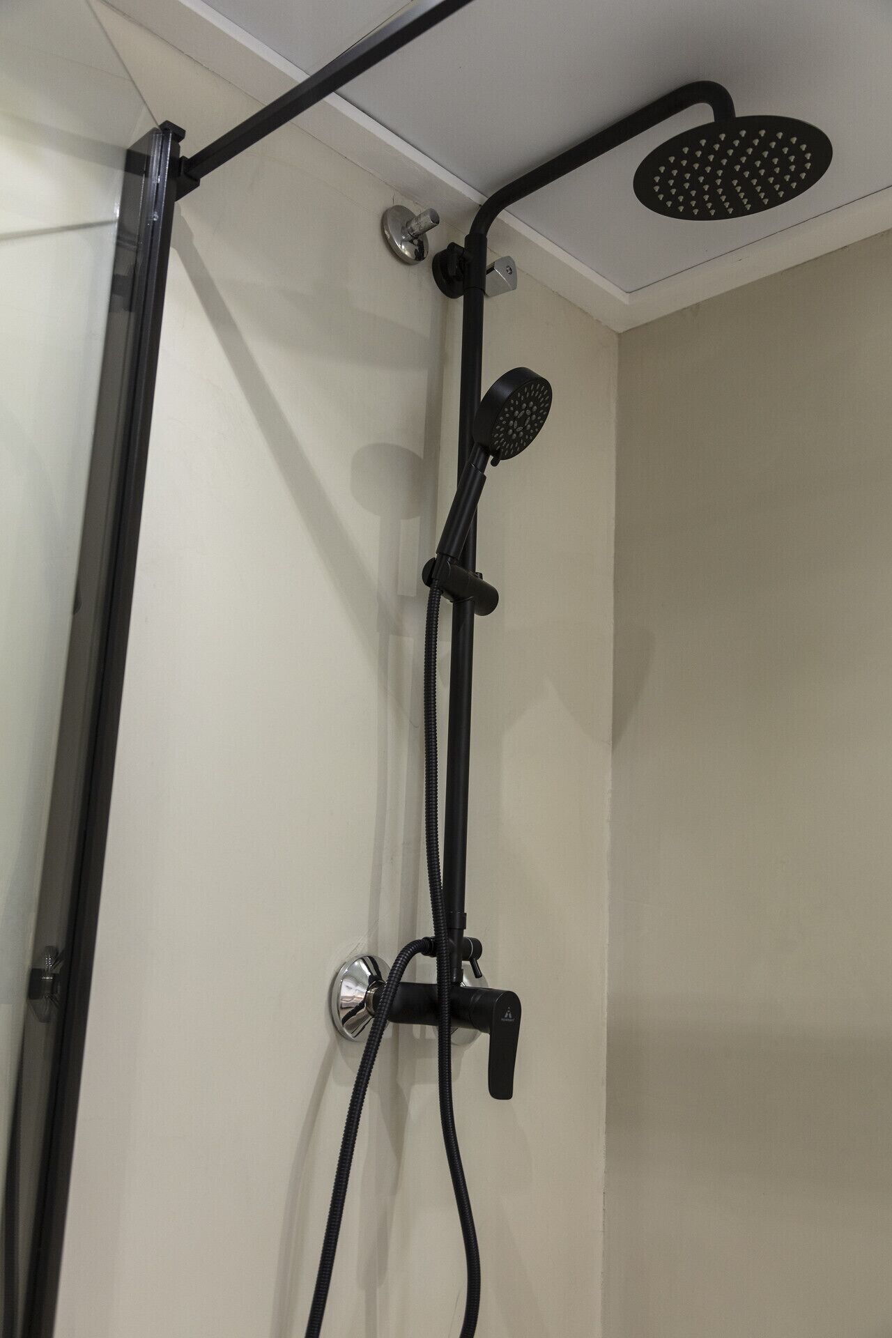 A shower with a handheld showerhead, a wall-mounted control, and a handheld shower attachment.