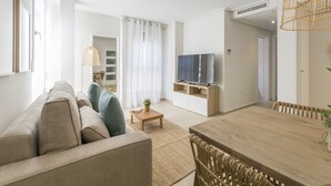 Ein modernes Wohnzimmer mit einer Couch, einem Esstisch und einem Fernseher.