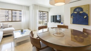 A modern living room with a glass dining table, white sofas, and a large window with curtains. - Apartment with amazing Ocean Views / Pool - Only families (Playa de Gandía)