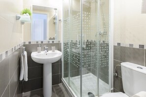 Enjoy a refreshing shower in the sleek bathroom with a pedestal sink and glass-enclosed shower area.