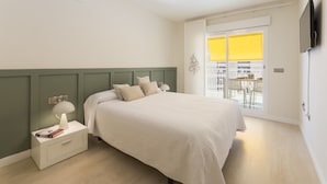Une chambre à coucher comprenant un lit, une table de chevet, une lampe et donnant sur un balcon avec des chaises.