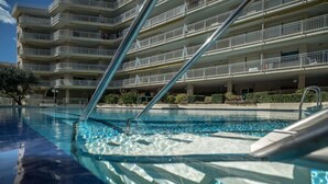 Une piscine avec vue sur un immeuble à plusieurs étages doté de balcons.