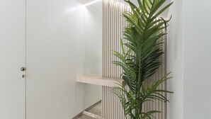 A hallway with a white door, a vertical wooden slat wall, and a potted plant.