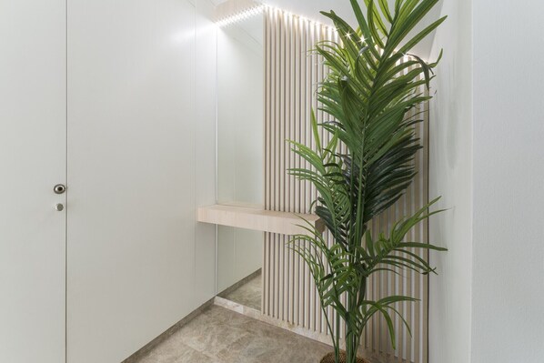 Un couloir avec une porte blanche, un mur composé de lattes de bois verticales et une plante en pot.
