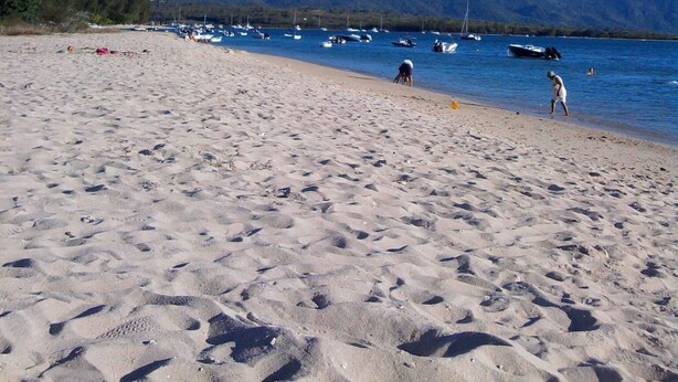 Una playa con barcos, montañas y cielos despejados.