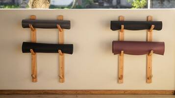 A wall-mounted rack with three rolled-up mats.
