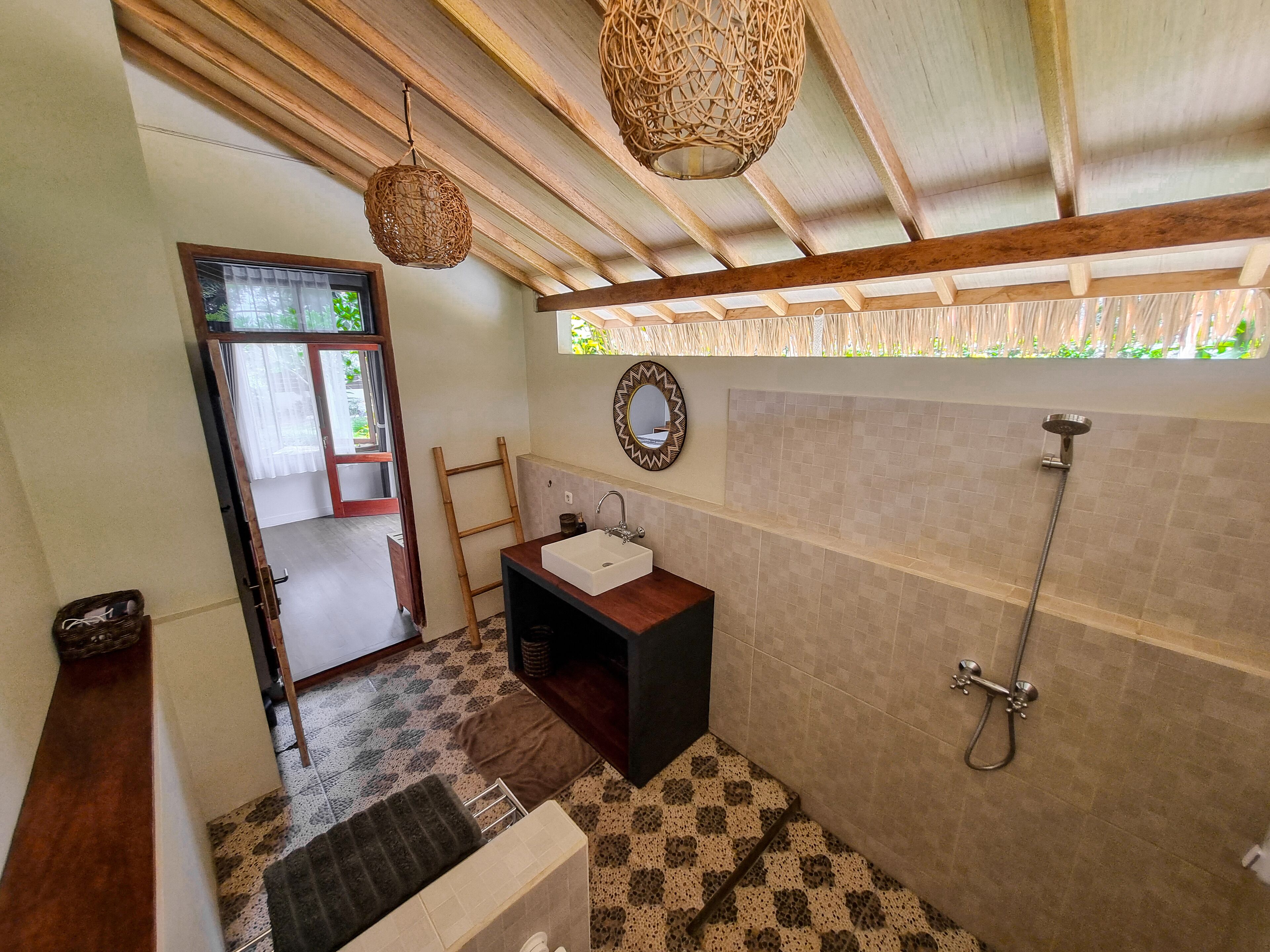 A bathroom with a wooden ceiling, a sink, a mirror, and a shower.