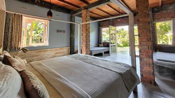 A bedroom with a large bed, a bench, and a view of the outdoors.