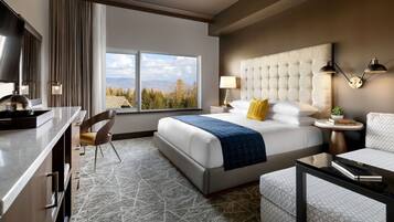Une chambre d’hôtel avec un grand lit, un bureau, une chaise, un canapé et une vue sur les montagnes.