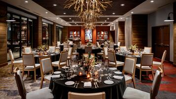 Un comedor formal con mesas redondas, sillas y una lámpara central de candelabro.