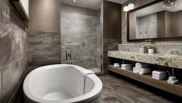 Une salle de bain moderne dotée d’une baignoire sur pieds, d’une douche à parois de verre et d’un meuble-lavabo avec un plan de toilette en marbre.