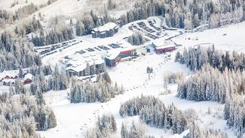 A snow-covered ski resort with multiple buildings, parking areas, and ski lifts.