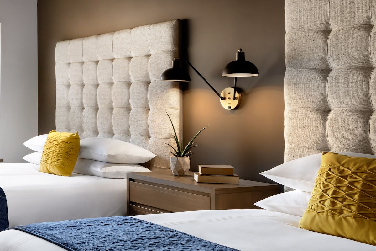 A bedroom with a tufted headboard, bedside lamps, and decorative pillows.