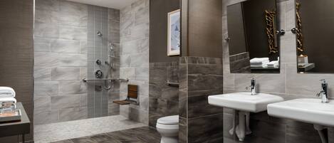 A modern bathroom with a shower, toilet, and two sinks.
