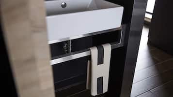 Un baño moderno con lavamanos blanco, piso oscuro y un perchero para toallas.