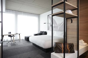 Een moderne hotelkamer met een groot bed, een bureau en een glazen scheidingswand.