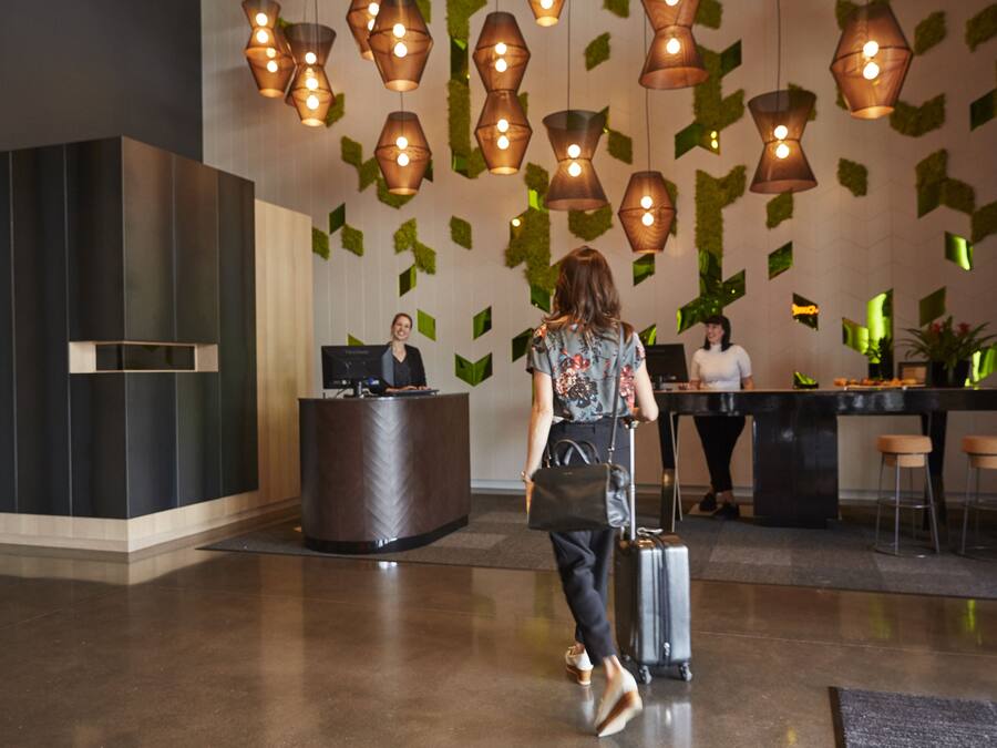 Eine Lobby mit einer Rezeption, einem Barbereich und einer Frau mit Koffer.