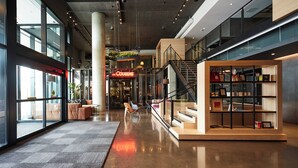 Un vestíbulo espacioso de diseño moderno, con una zona de recepción, asientos y una escalera que lleva a los pisos superiores.