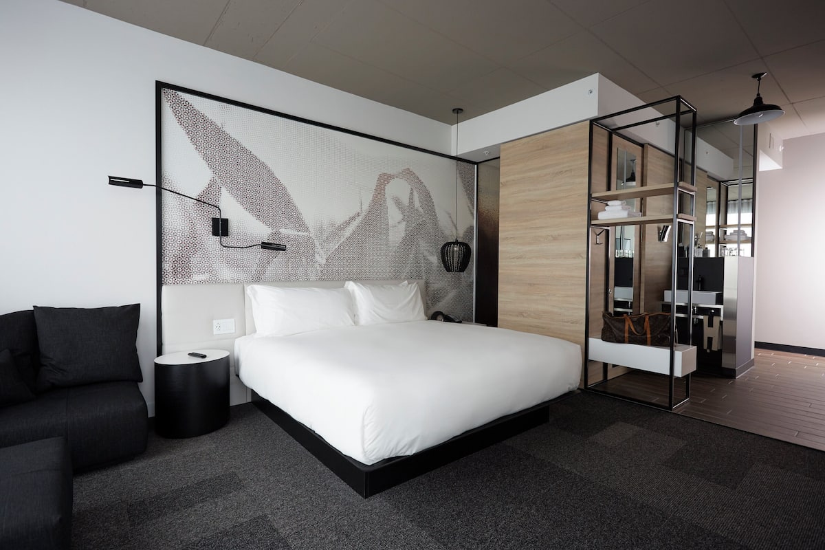 Ein modernes Schlafzimmer mit einem großen Bett, einer kleinen Couch und einem Schreibtisch.