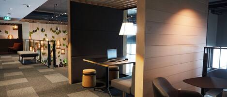 A modern office space with a desk, chair, and computer. There is a bench and a trash can.