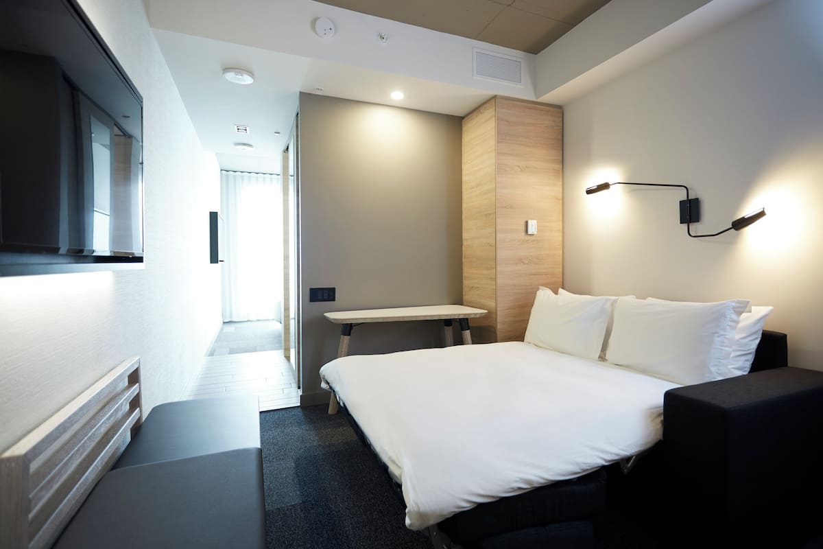Ein modernes Hotelzimmer mit einem großen Bett, einem Schreibtisch und einem Fernseher.