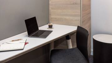 Un espace de travail avec un ordinateur portable, un carnet, un stylo et une tasse de café sur un bureau blanc.