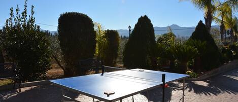 A ping pong table set up outdoors with a clear view of mountains in the background.