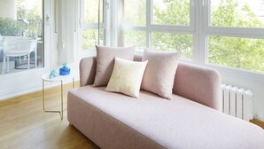 A modern living room with a pink sofa, white cushions, and a small side table with a blue object. - Playa de Ondarreta 2 by FeelFree Rentals (San Sebastián)