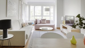 A modern living room with a sofa, coffee table, and TV. - Playa de Ondarreta 2 by FeelFree Rentals (San Sebastián)