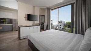 A modern hotel room with a large bed, a desk with a chair, a flat-screen TV, and a balcony with a view of the city. - Hanami Hotel Danang (Da Nang)