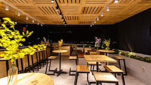 An outdoor dining area with wooden tables and benches, a sloped ceiling with wooden beams, and a view of the night sky. - Hanami Hotel Danang (Da Nang)