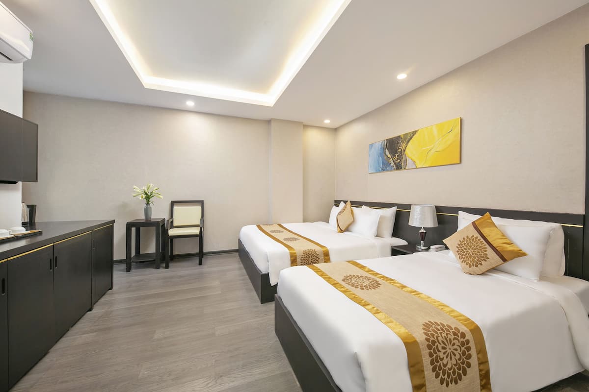 A hotel room with two beds, a desk, a chair, and a painting on the wall.